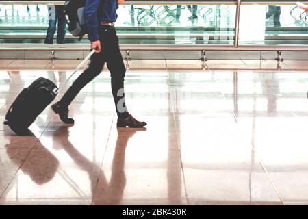 Traveler tirando la valigia in aeroporto moderno terminale. Viaggi e trasporti concetto Foto Stock