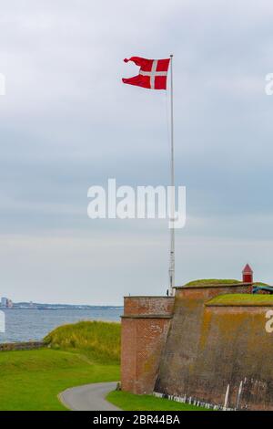 Bandiera danese vicino al castello di Kronborg in Danimarca. Bandiera danese vicino al famoso castello di Kronborg sulla costa del mare. Porto danese di Helsingor con Kro Foto Stock