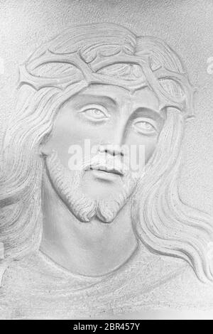 Bianco pietra bassorilievo del volto di Cristo con una corona di spine. Ideale per i concetti e gli sfondi Foto Stock