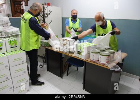 I volontari all'interno del magazzino della Caritas parrocchiale preparano pacchetti di cibo da distribuire alle famiglie bisognose perché non hanno soldi Foto Stock