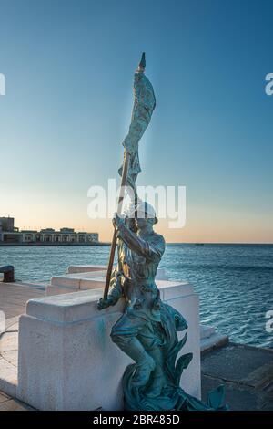 La statua di Bersagliere a trieste di fronte alla piazza dell'`unità. Bronzo di statua soldato di Bersagliere con bandiera a Trieste, vicino a unita d'Italia Foto Stock