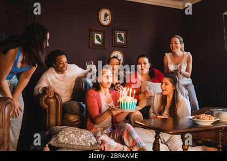 Piccolo gruppo di amiche per festeggiare un compleanno con una torta di compleanno durante i momenti di relax a casa. Foto Stock