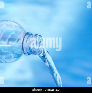 Profondità di campo. Soft focus di blu bottiglia versando acqua contro fresco e sfondo bluastro. Foto Stock