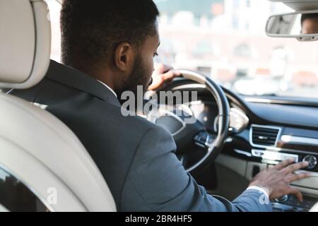 Unrecognizable Businessman Driving And Pushing Buttons Testing Car, Back View Foto Stock