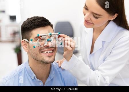 Visione dei pazienti con controllo da parte dell'optometro con struttura di prova in clinica Foto Stock