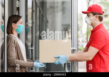 Consegna a domicilio durante il covid-19 Concept. Il cliente prende una scatola di cartone grande dal corriere. Foto Stock