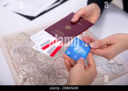 La gente la mano che regge il passaporto e carta di imbarco biglietto con carta bancomat sulla mappa del mondo Foto Stock