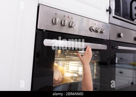 Bambina giocando con il sistema elettrico di un forno a microonde in cucina Foto Stock