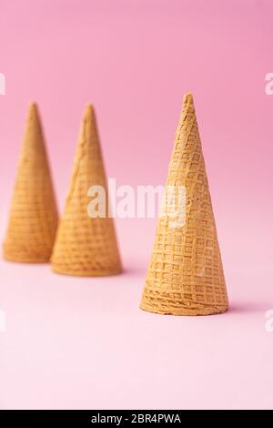 Tre coni di gelato alla farina di grano capovolti uno in primo piano e l'altro sullo sfondo su sfondo rosa. Concetto estivo. Foto Stock