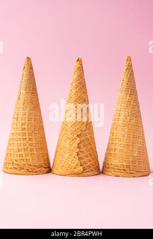 Tre coni capovolti per gelato alla farina di grano allineati verso il fondo su sfondo rosa. Concetto estivo Foto Stock