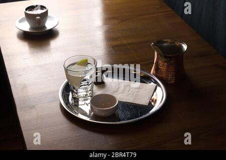 Un bicchiere di caffè con caffè e cioccolato accanto a un caffè con il latte in una tazza bianca collocato su un tavolo marrone Foto Stock