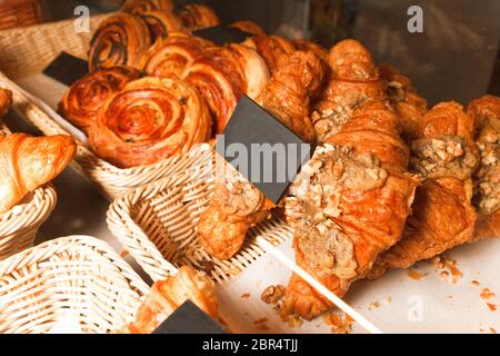 Deliziosi dolci appena sfornati in una pasticceria. Molti panini e croissant su un ripiano di una pasticceria Foto Stock
