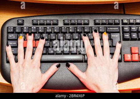 Le mani di una donna sulla tastiera di un computer in ufficio. Foto Stock