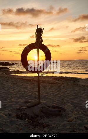 Tramonto dalla spiaggia di Espalmador Pass con un salvavita sospeso (Parco Naturale di Ses Salines, Formentera, Pityuses, Isole Baleari, Mar Mediterraneo, Spagna) Foto Stock