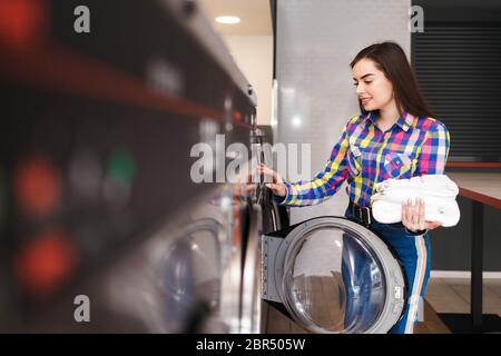 Ragazza nella lavanderia pubblica. Lavanderia automatica a pagamento nella lavatrice Foto Stock