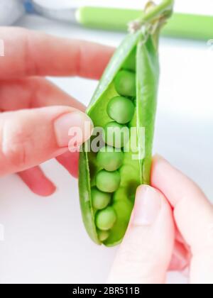 Giovane donna che scruta piselli verdi freschi. Cibo sano e stile di vita Foto Stock