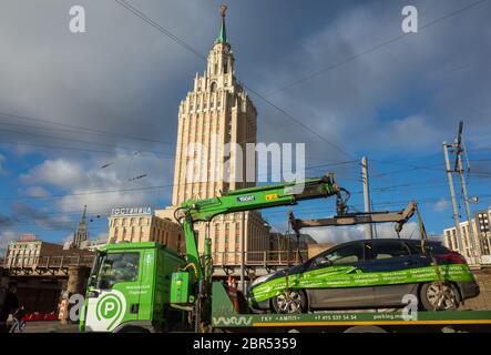 1 aprile 2019 Mosca, Russia. Un camion porta un'auto a un parcheggio sullo sfondo dell'edificio dell'hotel Leningradskaya sulla piazza di Foto Stock