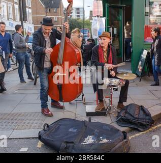 Due man band con contrabbasso, batteria di serpente e piatti che si affaccano su un angolo di strada per donazioni. Portobello Road, Notting Hill, West London, Regno Unito. Foto Stock