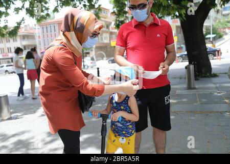 Ankara, Turchia. 20 Maggio 2020. I genitori aiutano il figlio a indossare una maschera su una strada ad Ankara, Turchia, il 20 maggio 2020. Mercoledì il Ministro della Sanità turco Fahrettin Koca ha riferito 972 nuovi casi COVID-19 e 23 ulteriori morti nel paese. Credit: Mustafa Kaya/Xinhua/Alamy Live News Foto Stock