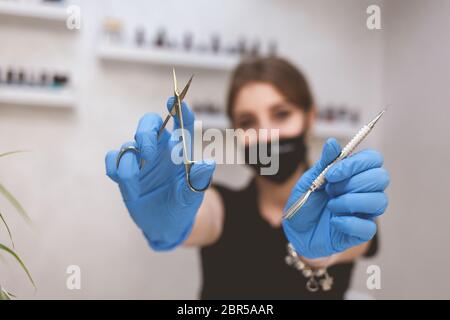 Donna mostra attrezzi manicure. Pinze e forbici per manicure nelle mani di un maestro Foto Stock