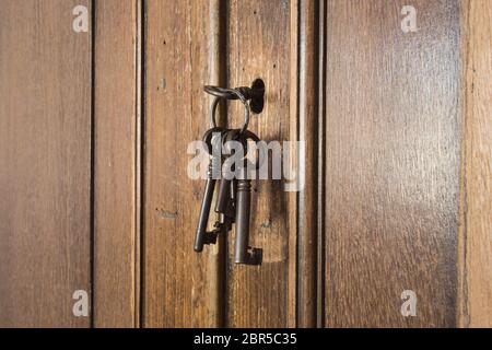 Vecchie chiavi arrugginite all'interno di un buco della serratura di un vecchio armadio antico. Primo piano di design vintage Foto Stock