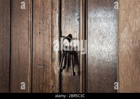 Vecchie chiavi arrugginite all'interno di un buco della serratura di un vecchio armadio antico. Primo piano di design vintage Foto Stock