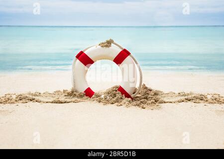 Salvagente sulla spiaggia sabbiosa di fronte al mare idilliaco Foto Stock