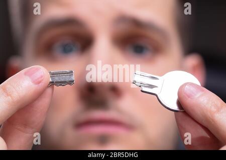 Ritratto di scioccato Man 's mano azienda argento chiave rotto Foto Stock