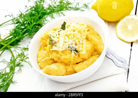 Gnocchi di zucca con salvia, limone, il formaggio e il burro in una ciotola, tovagliolo contro lo sfondo della luce pannello di legno Foto Stock