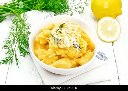 Gnocchi di zucca con salvia, limone, il formaggio e il burro in una ciotola, tovagliolo sulla tavola di legno sfondo Foto Stock