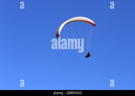 un parapendio sta volando di fronte ad un cielo blu Foto Stock