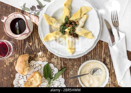 Cucina tipica italiana a. Casoncelli alla bergamasca (pasta farcita con briciole di pane, uova, parmigiano, carne di manzo macinata, salame) sulla piastra bianca nel resto locale Foto Stock