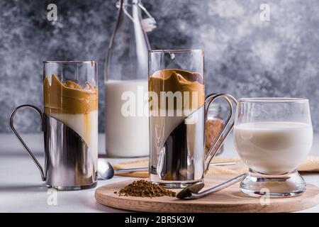 Latte espresso Dalgona con una schiuma fresca e soffice montata in bicchieri su sfondo grigio. Messa a fuoco selettiva. Foto Stock