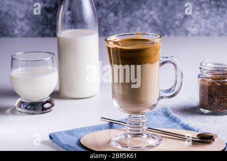 Caffè Dalgona con una schiuma fresca e soffice montata su sfondo grigio. Dalgona è una bevanda sudcoreana con caffè istantaneo montato, zucchero e latte. Foto Stock