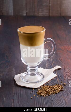 Caffè Dalgona con una schiuma fresca e soffice montata. Latte espresso in un bicchiere trasparente su un piano di ardesia grigio. Dalgona è una bevanda sudcoreana con un pippo Foto Stock