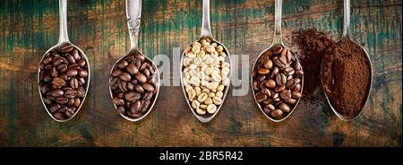 Assortimento di diversi caffè tostato e macinato fagioli visualizzati in argento vintage cucchiai in un panorama banner su legno rustico Foto Stock