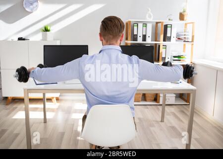 Imprenditore attraente esercizio con manubri in Office Foto Stock