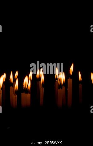 Molti Natale candele accese di notte su sfondo nero. Candela set isolato in sfondo nero. Gruppo di candele accese nel buio con Foto Stock