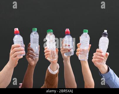 Gruppo di diverse persone che trattengono le bottiglie di acqua in una fila contro lo sfondo di colore verde Foto Stock