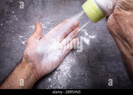 Close-up di mano d'uomo con polvere di talco su sfondo nero Foto Stock