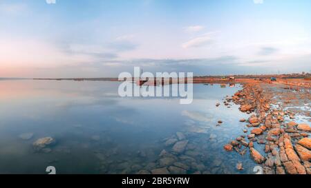 Vista panoramica del lago e la vecchia barca al tramonto di un giorno di estate Foto Stock