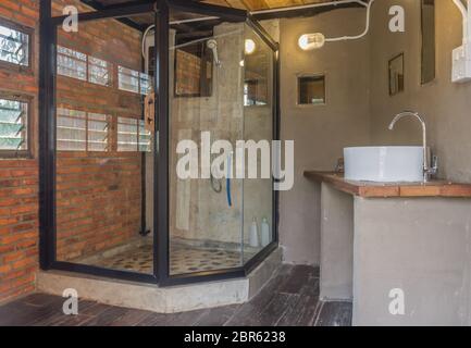 Bagno di vetro nel paese Loft Interior Design Room. Il design degli interni wc camera includono una lampada e windows e il rubinetto e lavandino. Interior design room in p Foto Stock