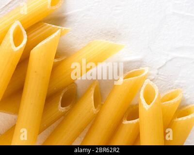 La pasta grezza come sfondo di cibo. Italian Penne Rigate Maccheroni testurizzato su sfondo bianco. La pasta secca selezione vicino. Vista superiore o laici piana w Foto Stock