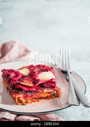 Ortaggio pranzo Rainbow lasagne sulla piastra di rosa. Idee e ricette per vegetariani sani per pranzo o cena. Lasagne con barbabietola, zucca, funghi, r Foto Stock