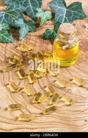 Capsule oblunghe gelatinose trasparenti di olio di pesce sono state sparse sullo sfondo di legno. Acidi grassi polinsaturi Omega-3-essenziali. Semi di lino oi Foto Stock