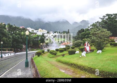 Furnas, Azzorre, Portogallo - 13 gennaio 2020: Sorgenti termali vulcaniche in Furnas portoghese. Vapore proveniente dalle piscine d'acqua. Case e colline sullo sfondo. Decorazione di Natale, cespugli verdi e alberi. Foto Stock