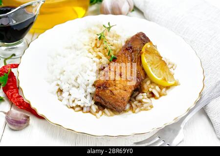 Rosa salmone con il miele, il succo di limone e salsa di soia, riso bollito, fetta di limone e un rametto di timo in una piastra, peperoncino, aglio, prezzemolo, un tovagliolo Foto Stock