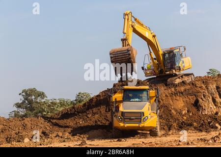 Costruzioni industriali earthworks macchina livellatrice caricamento della terra in grandi autocarri Foto Stock