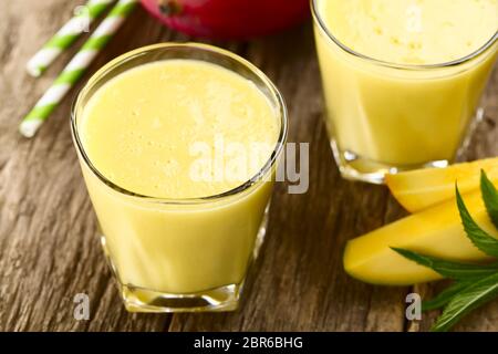 Rinfrescante e mango frullato di yogurt in bicchieri con cannuccia (fuoco selettivo, la messa a fuoco di un terzo nel primo drink) Foto Stock