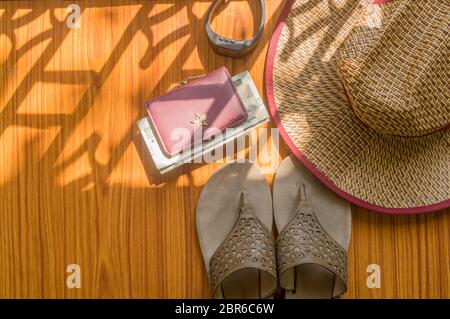 Pronto a viaggiare. Vista dall'alto sullo sfondo della spiaggia di accessori essenziali per le donne moderne in un tavolo di legno. Infradito, borsa di denaro, valuta, un orologio da polso e un Foto Stock